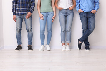 Group of people in stylish jeans near white wall indoors, closeup