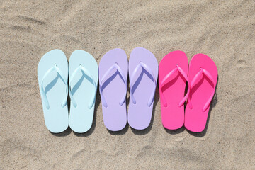 Fototapeta na wymiar Stylish colorful flip flops on sand outdoors, flat lay