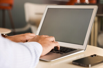 Man working on laptop at table in office, closeup