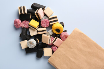 Paper bag with tasty liquorice candies on light blue background, top view