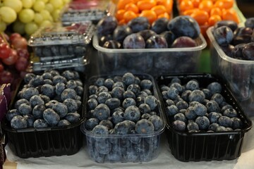 Fresh blueberries and plums on counter at market, closeup