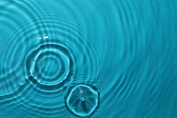 Rippled surface of clear water on light blue background, top view