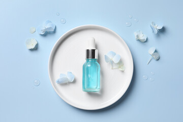Bottle of cosmetic serum and beautiful flowers on light blue background, flat lay