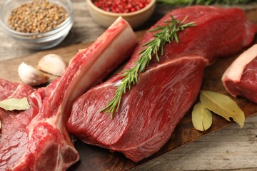 Pieces of raw beef meat and spices on wooden table