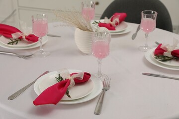 Color accent table setting. Glasses, plates, cutlery and pink napkins on table