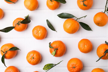 Fresh ripe tangerines with green leaves on white table, flat lay