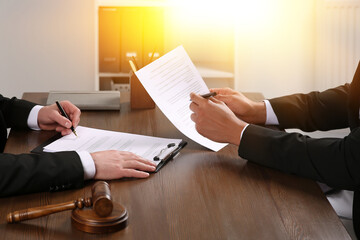 Law and justice. Lawyers working with documents at wooden table in office, closeup