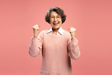 Portrait smiling funny senior woman, happy modern grandmother holding hands win something...