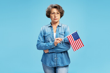 Portrait serious confident senior woman holding American flag celebration Independence Day isolated...