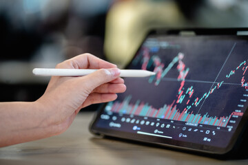 Investor points to the stock market index digital tablet screen to analyze the stock chart for...