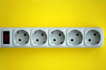 White electrical multi plug extender with european socket on bright yellow background close up