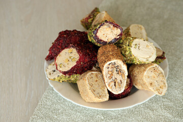 Many rolls of turkish delight with different flavors and fillings in white plate on table. Cuts of...