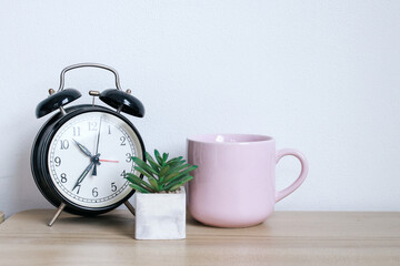 Alarm clock, succulents and a mug on wooden table, minimal stylish working desk