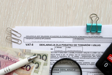 Declaration for tax on goods and services VAT-8 form on accountant table with pen and polish zloty money bills close up