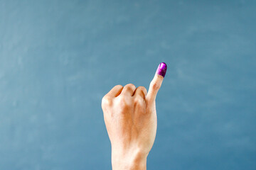 Man's little finger after voting on Indonesia's presidential election on grey background