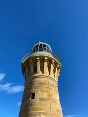  Lighthouse on the island at daytime. Sandstone lighthouse at the top of a hill. Coast ligthouse...