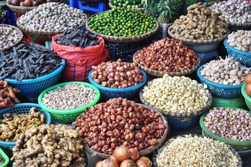 Onions, garlic, shallots, seed pods and other bulk natural ingredients for sale at an outdoor market in Southeast Asia