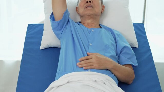 Elderly Asian male patient with symptoms of illness, headache, fever, lying on a hospital bed, being treated at the hospital by health care professionals and doctor's care, health insurance.