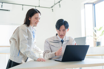 パソコンを見る作業着を着たビジネスマンたち