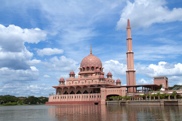 A stunning view of the Putra Mosque in Malaysia. The mosque is a large, pink building with a large dome and four minarets. It is located on an artificial island and lake in Putrajaya.