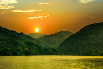 Beautiful mountain landscape silhouette at sunrise..Colorful sky cloud scene and golden lake water...