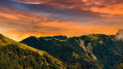 Rolling mountain,glow golden sky and winding valley grass view form a vast scenic scene. High quality photo photography in Hehuanshan,Nantou,Taiwan.Use in branding, screensavers, websites, etc.