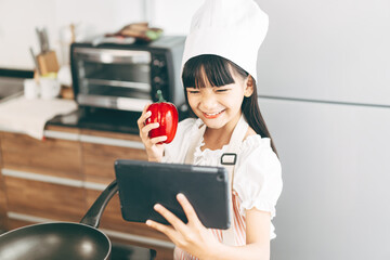 Little asian girl with chef hat and apron cooking at home kitchen