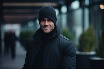 young bearded handsome man in a hat and raincoat outdoors. Close-up.