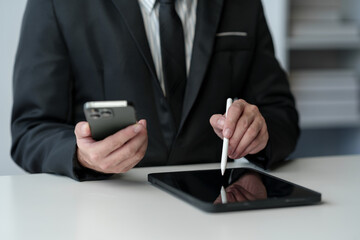 Businessman working on laptop computer and tablet on table at office. Working online. Using pen, index finger on digital tablet screen. Work mindset concept, lifestyle idea