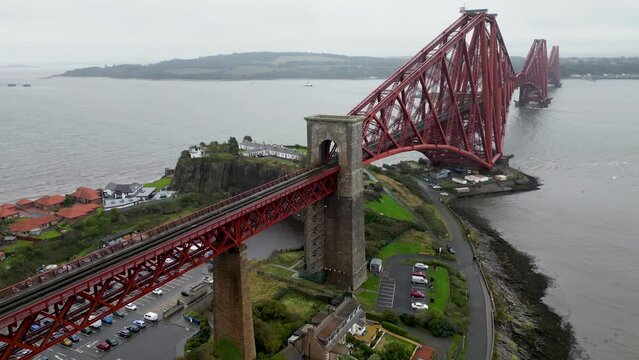 The Forth rail bridge is a cantilever railway bridge across the Firth of Forth. Cinematic aerial drone shot of Forth Rail Bridge, Scotland, Forth Road bridges in background, rainy day.