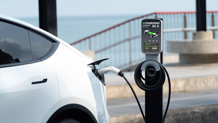 Electric car recharging battery at outdoor EV charging station for road trip or car traveling by the seascape, alternative and sustainable energy technology for eco-friendly car. Perpetual