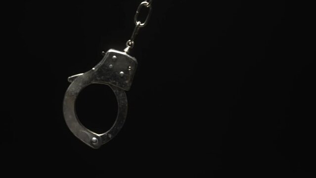Close-up of Handcuff Swinging in Black Background
