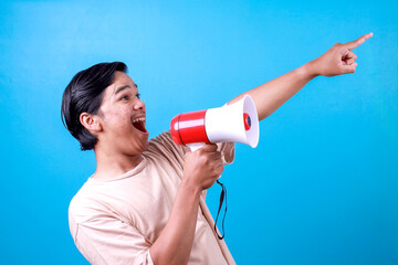 Excited young man speak loudly using megaphones while pointing to the empty space announces good...