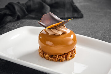 Sophisticated hazelnut praline mousse cake with a smooth glaze and chocolate decor, presented on a...