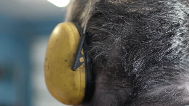 Factory Worker Using Hearing Protection Ear Muffs Closeup