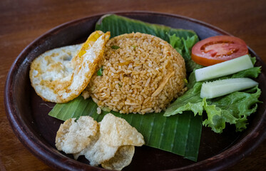 Asian Fried Rice, Nasi Goreng served with cucumber, tomato, egg and crackers. Nasi goreng is Indonesia fried rice dish.