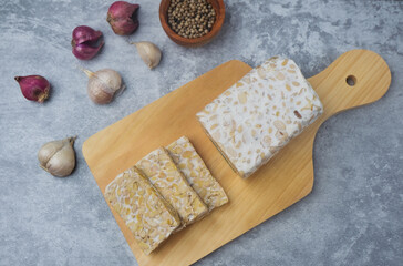 Slices of raw Tempeh in wooden chopping board. Tempe is Indonesian Food made from farmented soybean.
