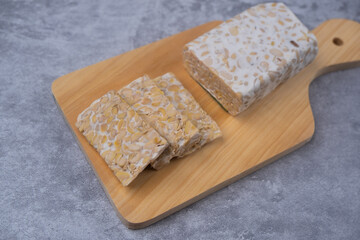 Slices of raw Tempeh in wooden chopping board. Tempe is Indonesian Food made from farmented soybean.