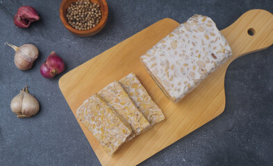 Slices of raw Tempeh in wooden chopping board. Tempe is Indonesian Food made from farmented soybean.