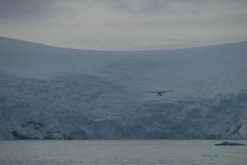 Aircraft flying against the backdrop of Antarctic ice walls