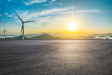 Asphalt road square and wind turbines with mountain landscape at sunset. High Angle view.