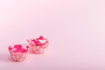 Paper cupcake tins with decorative hearts on a pink background. Concept for Valentine's day, birthday, mother's day.