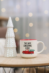 Cup of hot tea on caffee table in living room. Christmas home interior. Ceramic christmas tree. 