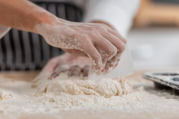 professional Chef sifting flour powder and sprinkling ingredients on massaging dough for bakery...