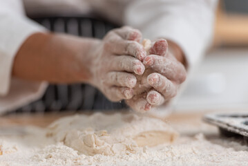 professional Chef sifting flour powder and sprinkling ingredients on massaging dough for bakery cooking. Chef show dirty finger hand sifting flour wheat and kneading dough mixing powder.