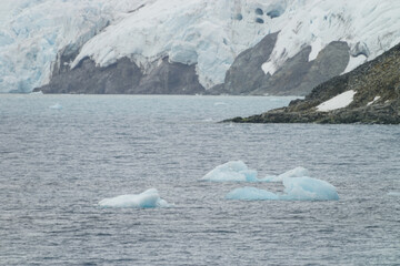 Antarctic ice walls and drift ice floating in the sea visible in the distance