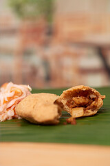 A tempting photo of a savory Salvadoran pastelito, showcasing its authentic taste and culinary artistry, set in a restaurant-style ambiance on a wooden surface accentuated by a leaf