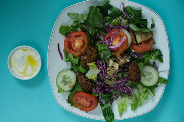 Salad de falafel, salad is an appetizer made of fresh raw vegetables such as tomatoes, lettuce, cucumber, olives, purple cabbage, dressing with yogurt, lemon juice and olive oil. Italian food. 