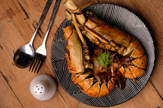 Lobster saus lada hitam or Lobster in black pepper sauce. Served on a ceramic plate. Stainless steel cutlery. Indonesian food.