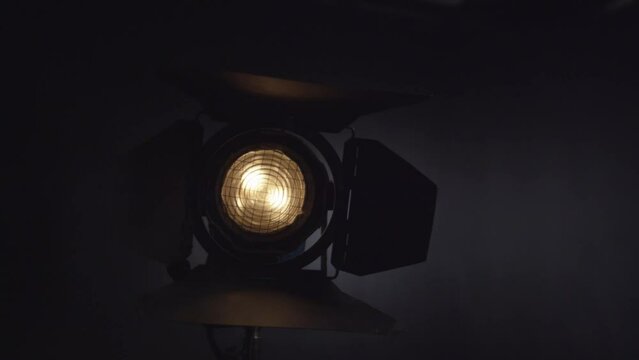Closeup footage of a studio spotlight lights slowly on black background